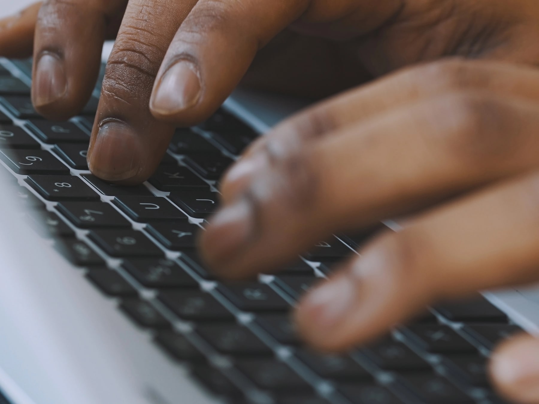 Close up of man's hands as he types on the keyboard.